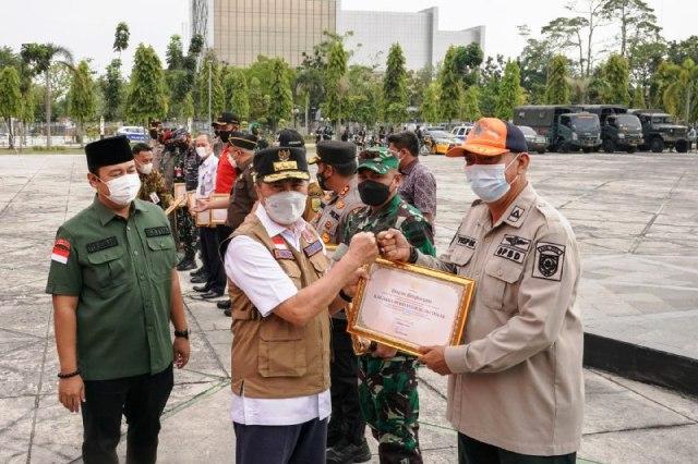 Gubri Syamsuar menyerahkan piagam penghargaan kepada Satgas Penanggulangan Karhutla./F-PEMPROV RIAU